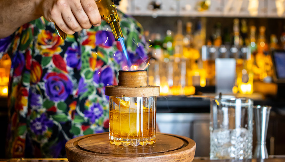 bartender creating a fancy cocktail with a torch