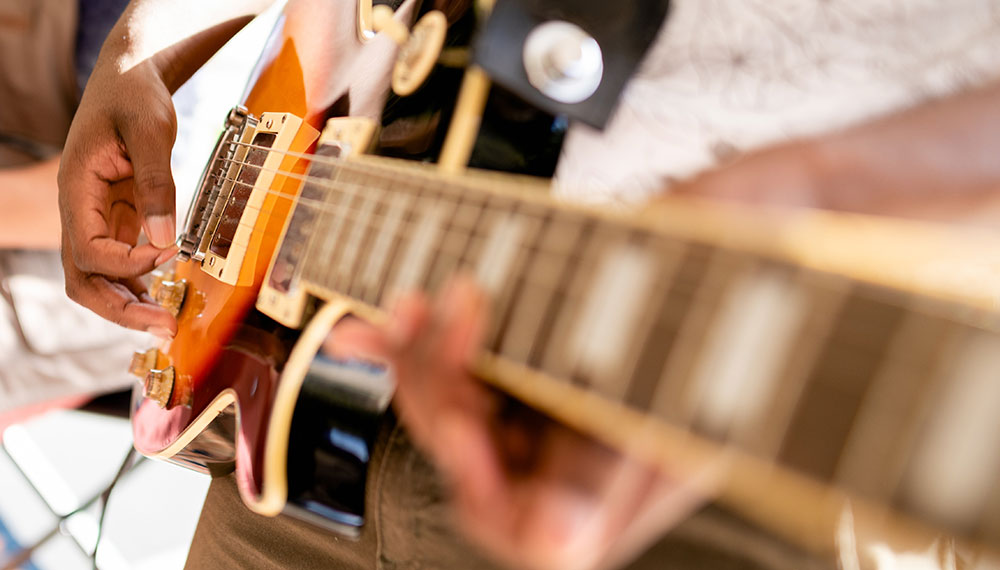 closeup of guitar fretboard and guitarist playing