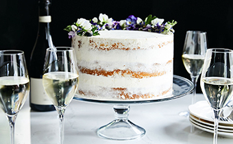 white frosted cake with flowers and champagne glasses
