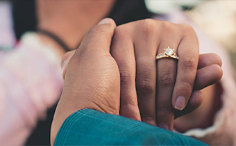 close up of a couple holding hands with a wedding ring